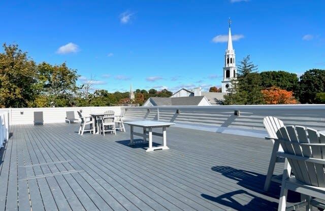 a roof deck with a table and chairs and a church in the background