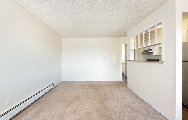 a spacious living room with white walls and a carpeted floor