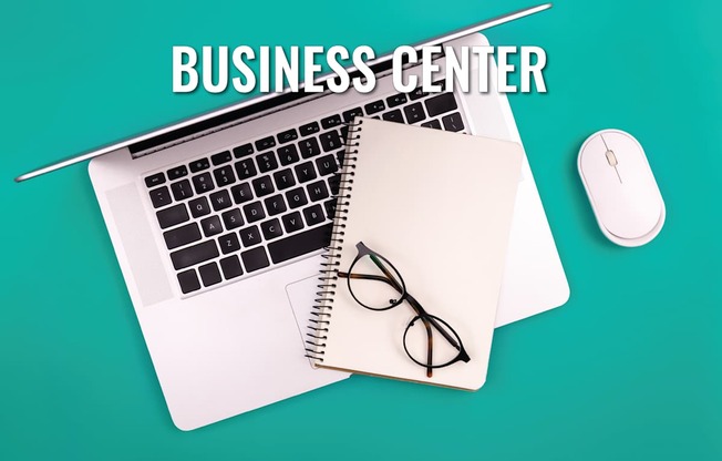 A business center setup with a laptop, mouse, and glasses on a notepad.
