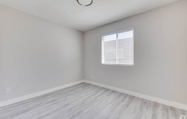 an empty room with wood floors and a window