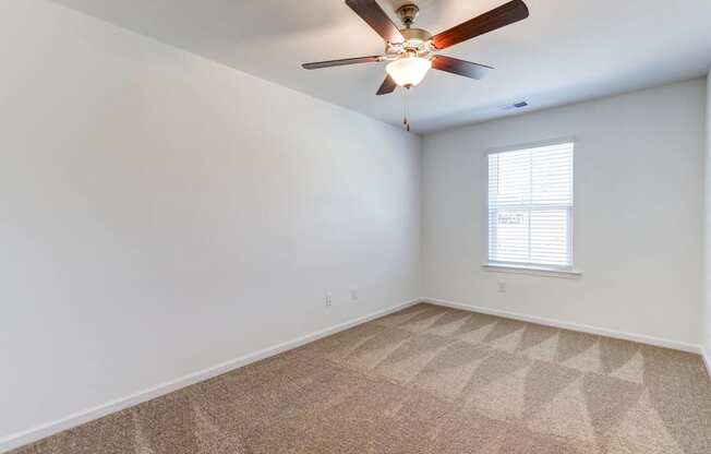 an empty room with a ceiling fan and a window