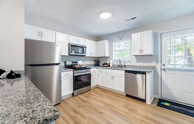 A kitchen with white cabinets and a granite counter top.