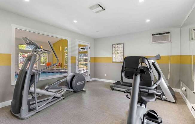 A gym with a treadmill, elliptical trainer and a stationary bike.