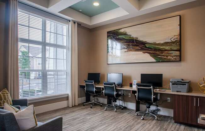 a workspace with computers and a large painting on the wall