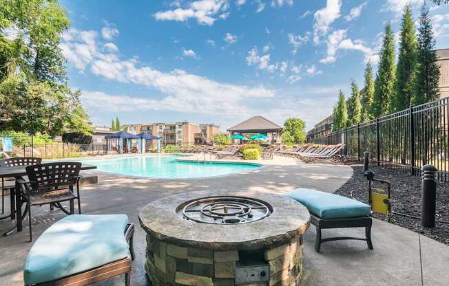 A pool area with a fountain in the middle and chairs around it.