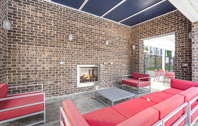 a patio with red couches and chairs and a fireplace