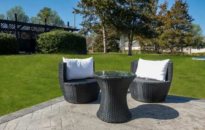 a patio with chairs and a table with pillows on it