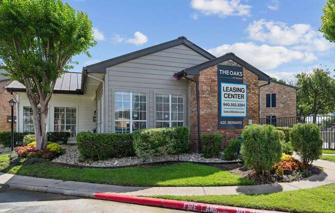 The Oaks of Denton Leasing Office is surrounded by lush hedges and lawns in Denton, TX