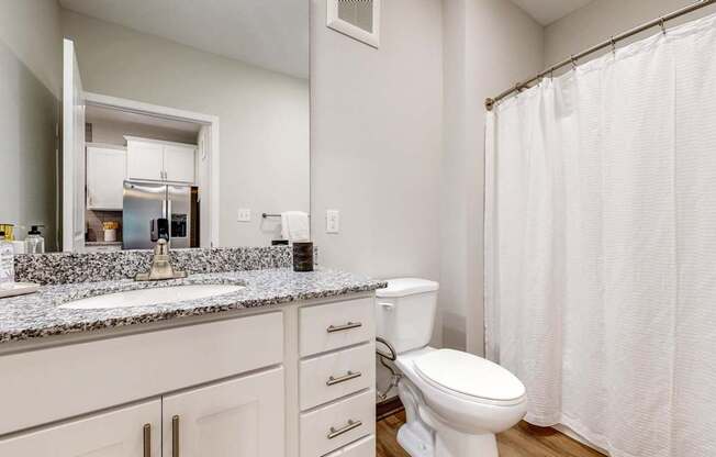 A white bathroom with a toilet, sink, and shower.