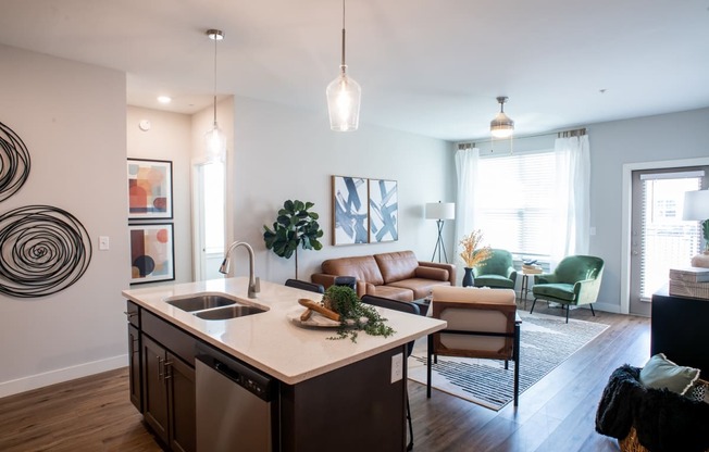 a kitchen with an island in front of a living room with a couch and chair