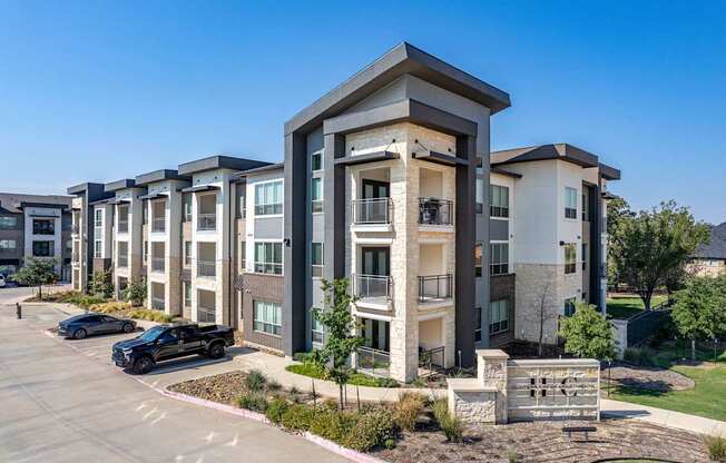 A black car is parked in a parking lot in front of a building.