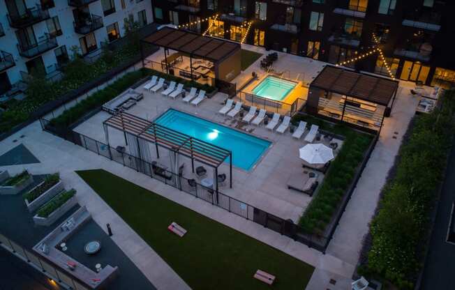 a pool and lounge chairs in a yard of an apartment building