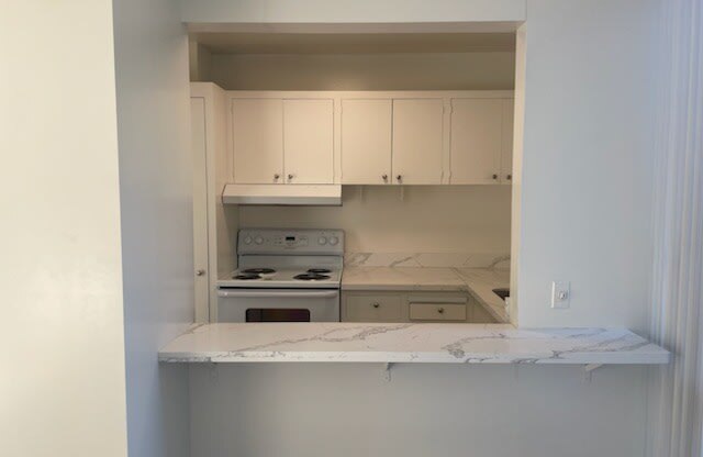 an empty kitchen with white cabinets and a white counter top