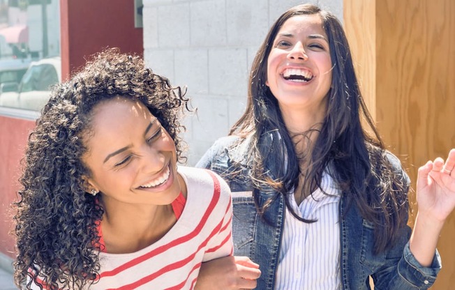 two young women laughing and smiling in front of a door