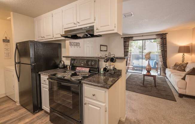 A modern kitchen with black appliances and white cabinets at Bishop's Court Apartments, California, 95670