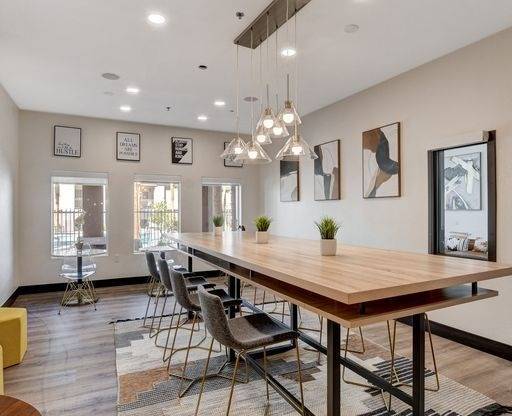 A modern dining room with a long wooden table and chairs.