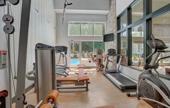 Gym with exercise equipment and a large window with a pool in the background at Governor's Park, Fort Collins, 80525