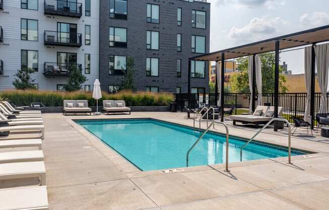 a swimming pool with chaise lounge chairs and a building in the background