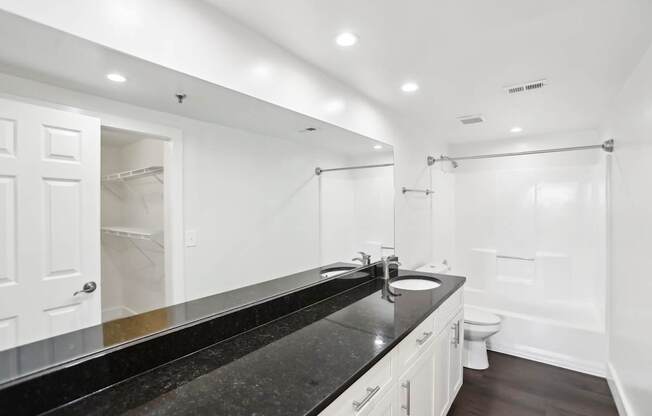 A bathroom with a black countertop and white walls.