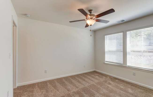 an empty room with a ceiling fan and a window