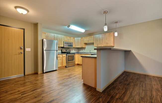 a kitchen with wood flooring and a stainless steel refrigerator. Fargo, ND Urban Plains Apartments