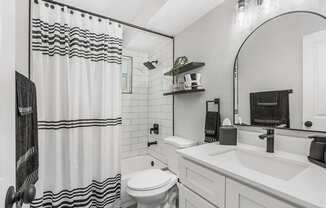A white bathroom with a black and white shower curtain.