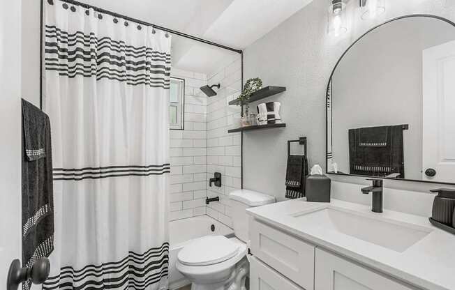 A white bathroom with a black and white shower curtain.