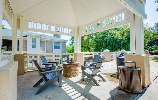 a covered patio with chairs and tables and a house in the background