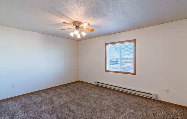 a bedroom  with a window and ceiling fan.  Fargo, ND Sunwood Apartments  | Living and kitchen Fargo, ND Sunwood Apartments