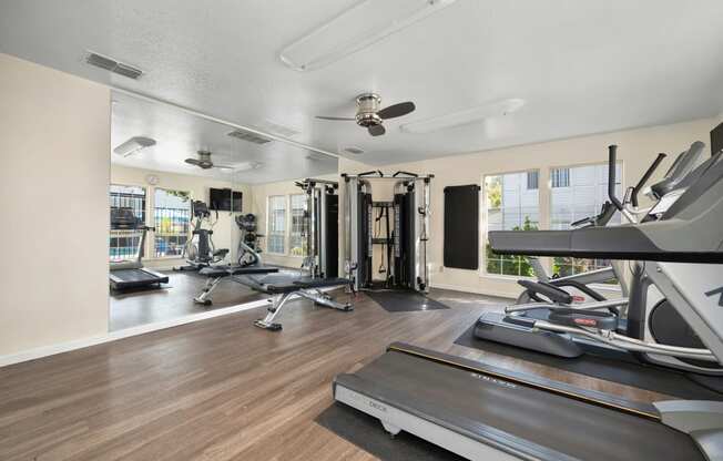 a gym with treadmills and other exercise equipment and windows