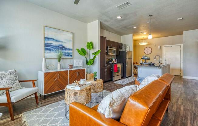 A living room with a brown leather couch and a painting on the wall.