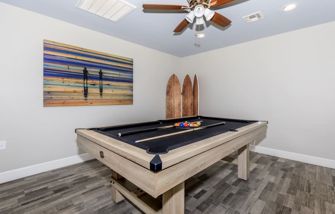 a game room with a pool table and a surfboard on the wall