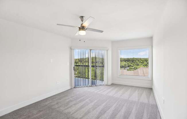 A room with a ceiling fan, carpeted floor, and beautiful view.