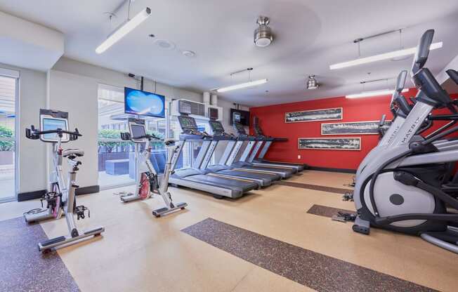 two treadmills and other exercise equipment in a gym with a tv