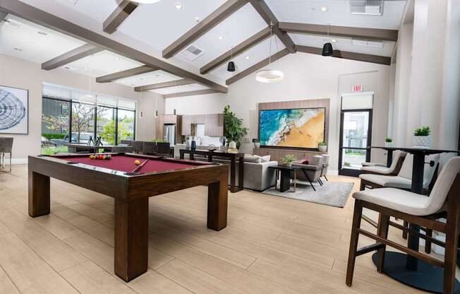 A room with a pool table and a painting of a beach on the wall.