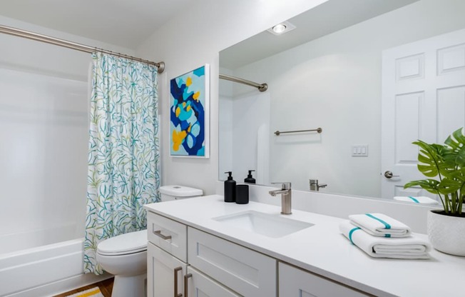 A bathroom with a white counter top and a white toilet.