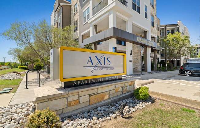 A sign for Axis Apartments in front of a building.