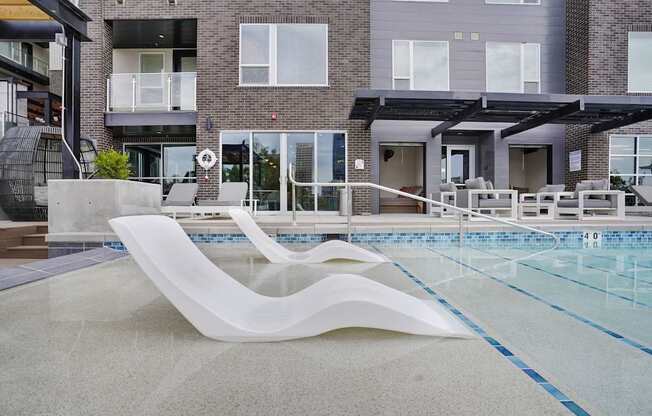 A modern poolside lounge chair sits in front of a building.