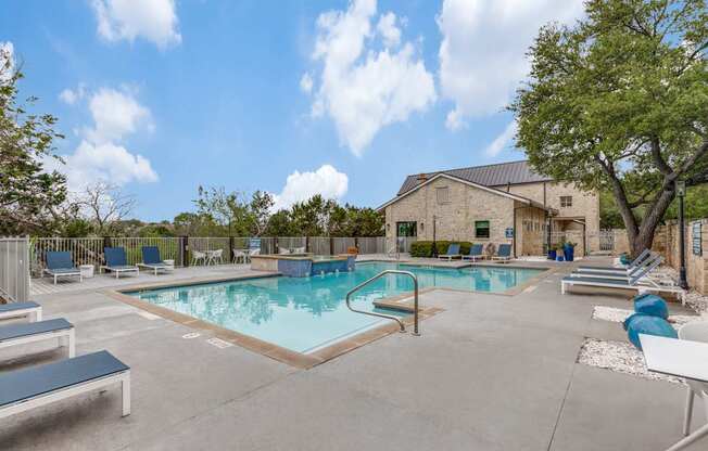 A large outdoor swimming pool with lounge chairs and a building in the background.