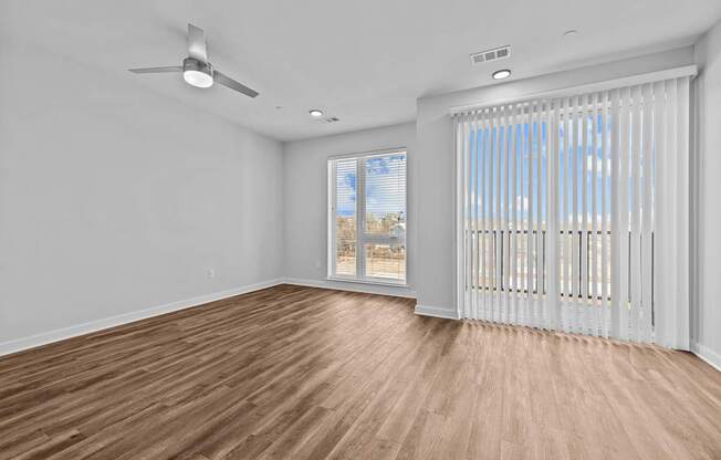 A room with a ceiling fan and a window with blinds.