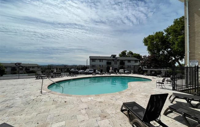 A pool surrounded by a patio and chairs.