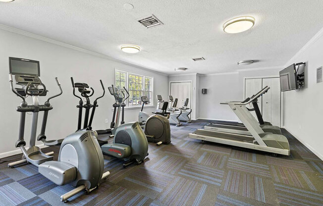 a gym with various exercise machines and a tv