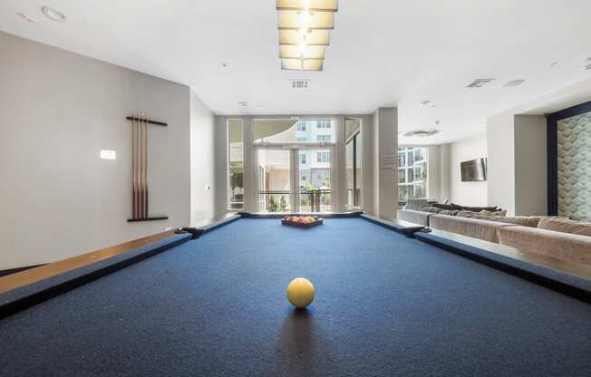 a game room with a blue pool table and a yellow ball on top of it