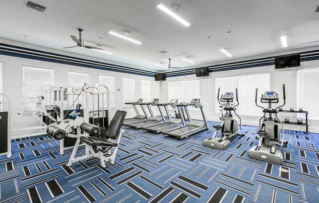 a gym with weights and cardio equipment in a room with windows