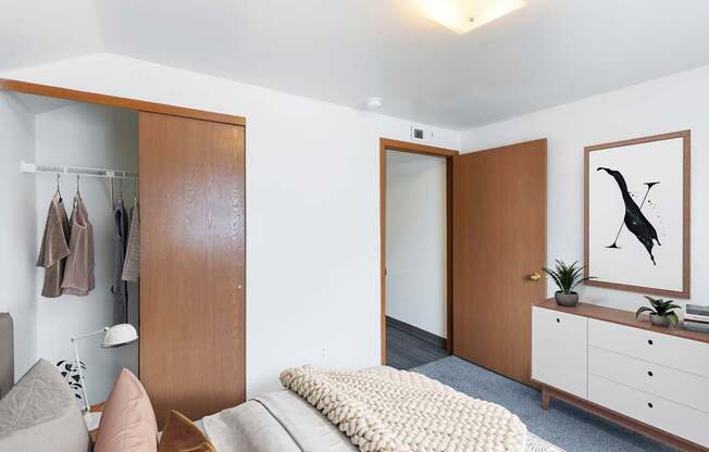 A bedroom with a large closet, dresser and painting at Shiloh Glen Apartments in Billings, MT.
