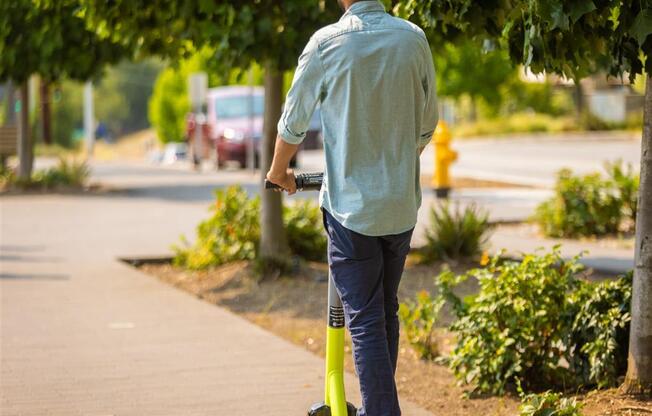 a man riding a scooter down a sidewalk