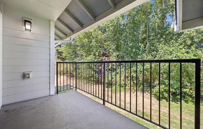 A balcony with a black railing and a white wall.