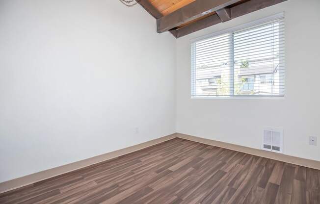 Interior room with hardwood floors, vaulted ceiling and a window and white walls at Foster Creek apartments