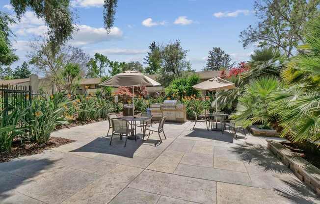 a patio with tables and umbrellas in a garden at Summerwood Apartments, Santa Clara, California