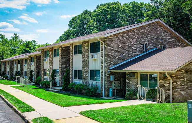 a brick apartment building with a sidewalk and grass
